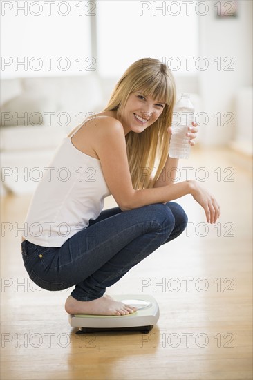 Portrait of woman crouching on weight scales.
Photo : Jamie Grill