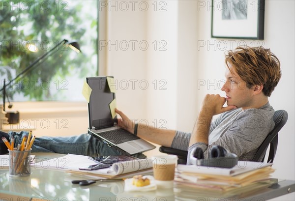 Man using laptop in home office.
Photo : Daniel Grill