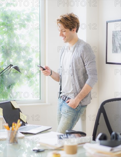 Man using phone in home office.
Photo : Daniel Grill