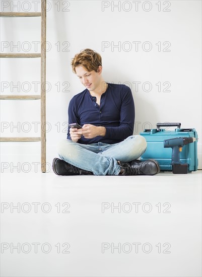 Man with toolbox using phone.
Photo : Daniel Grill