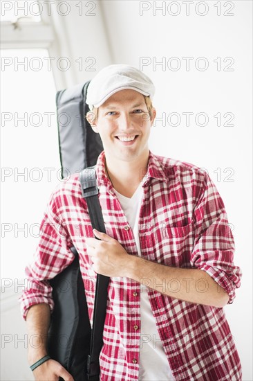 Portrait of man carrying guitar bag.
Photo : Daniel Grill