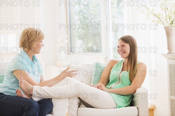 Mother and adult daughter sitting on sofa and talking.
Photo : Daniel Grill