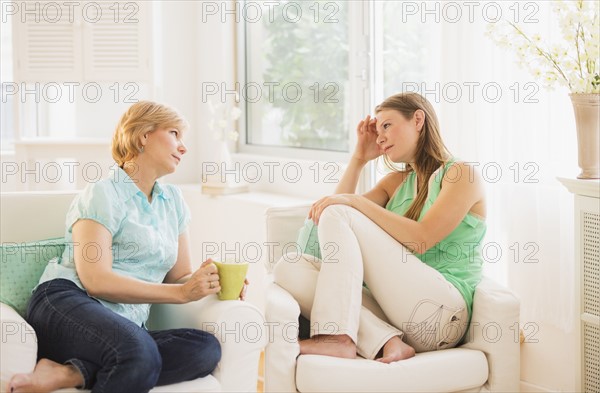 Mother and adult daughter sitting on sofa and talking.
Photo : Daniel Grill