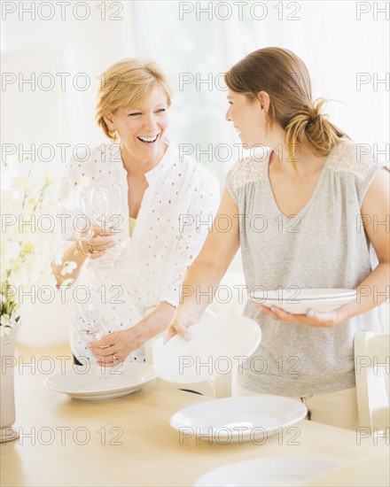 Mother and adult daughter setting table for dinner.
Photo : Daniel Grill