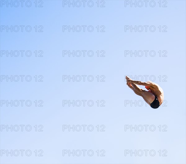 Athletic swimmer mid-air against blue sky.
Photo : Daniel Grill