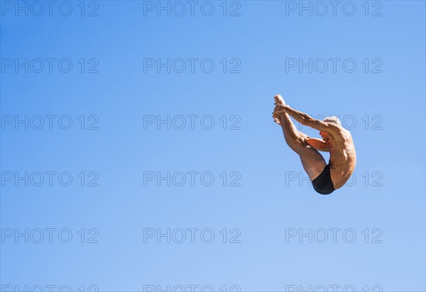 Athletic swimmer mid-air against blue sky.
Photo : Daniel Grill