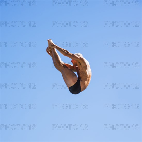 Athletic swimmer mid-air against blue sky.
Photo : Daniel Grill