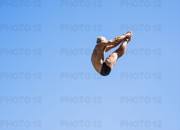 Athletic swimmer mid-air against blue sky.
Photo : Daniel Grill