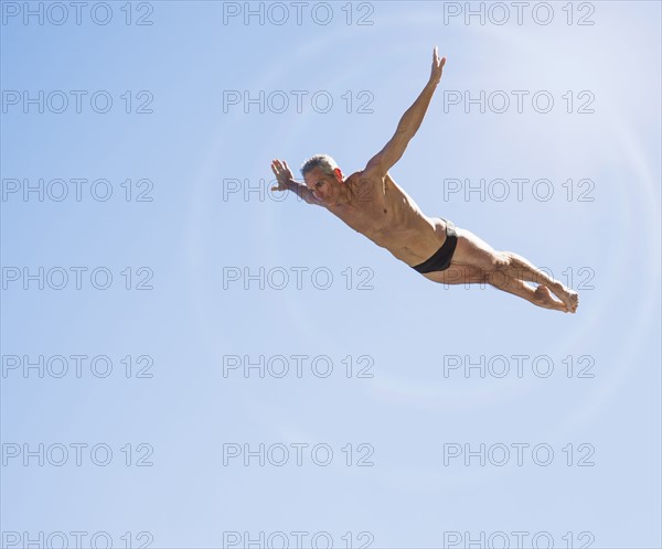 Athletic swimmer mid-air against blue sky.
Photo : Daniel Grill