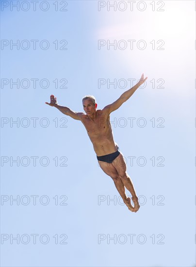 Athletic swimmer mid-air against blue sky.
Photo : Daniel Grill