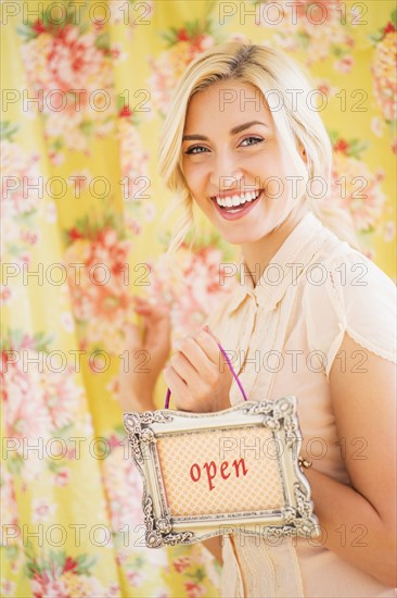 Teen (16-17) girl holding open sign.
Photo : Daniel Grill