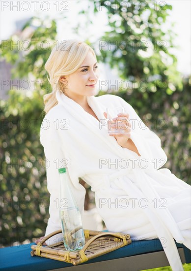 Teenage girl (16-17) wearing bathrobe sitting in garden.
Photo : Daniel Grill