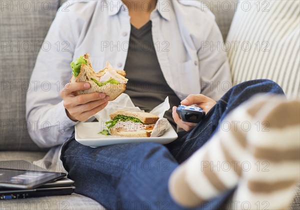 Teenage boy(16-17) eating sandwich and watching tv.
Photo : Daniel Grill