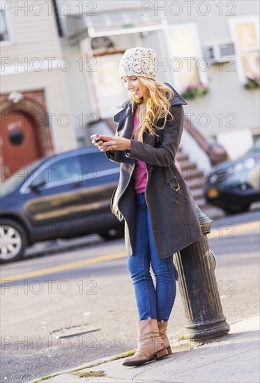 Portrait of woman standing by fire hydrant and text messaging. USA, New York City, Brooklyn, Williamsburg.
Photo : Daniel Grill