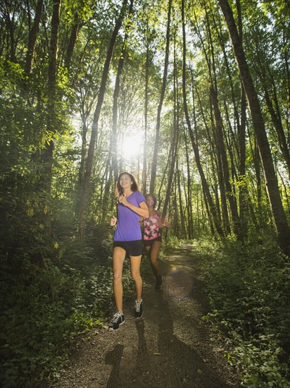 Two young women jogging in forest. USA, Oregon, Portland.