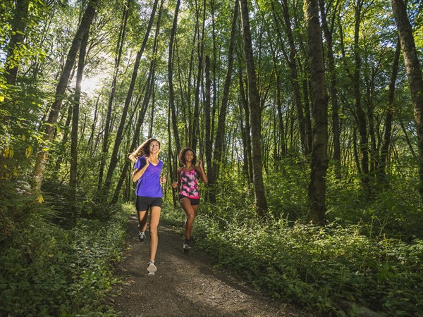 Two young women jogging in forest. USA, Oregon, Portland.