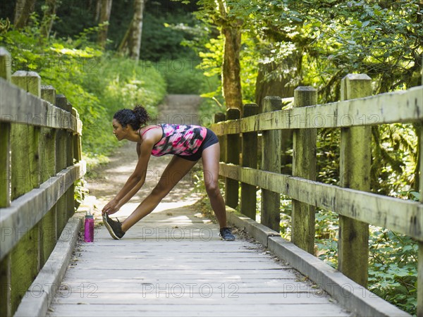 Young women stretching on footbridge. USA, Oregon, Portland.