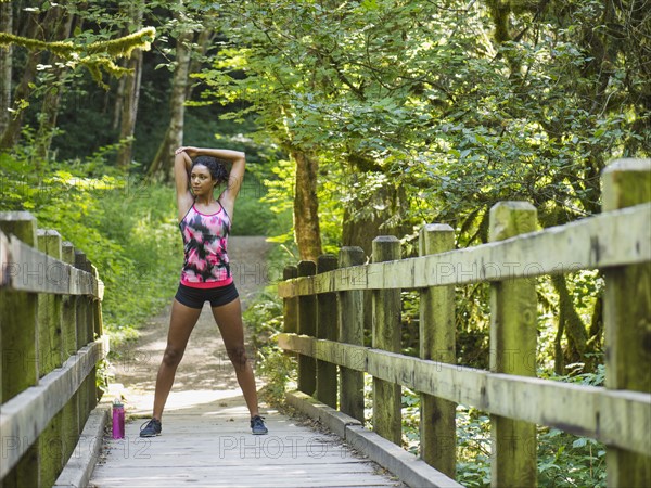 Young women stretching on footbridge. USA, Oregon, Portland.