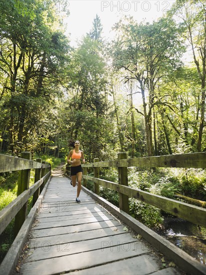 Young woman jogging on footbridge. USA, Oregon, Portland.