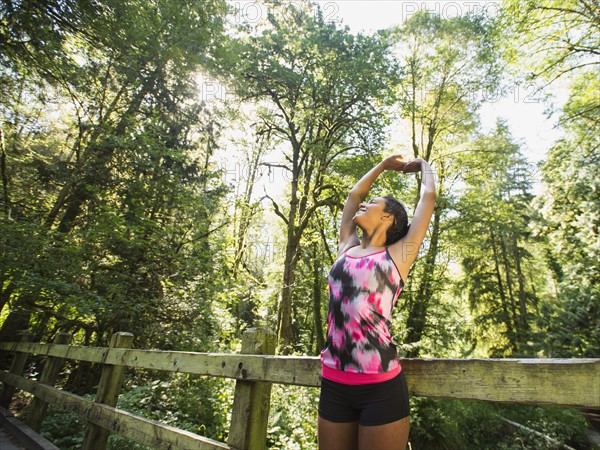 Portrait of young woman stretching on footbridge. USA, Oregon, Portland.