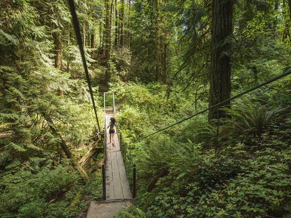 Rear view of young woman jogging in forest. USA, Oregon, Portland.