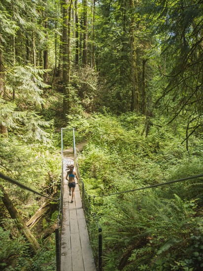 Rear view of young woman jogging in forest. USA, Oregon, Portland.