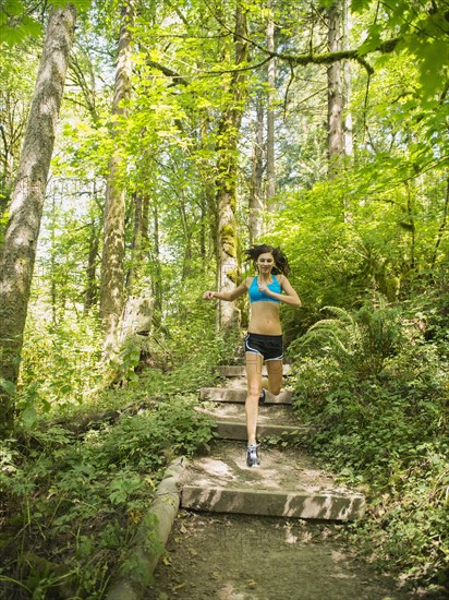 Young woman jogging in forest. USA, Oregon, Portland.