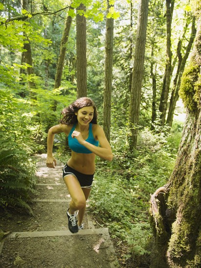 Young woman jogging in forest. USA, Oregon, Portland.