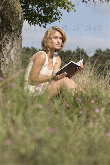 Woman sitting on grass and reading book. Netherlands, Gelderland, Hatertse Vennen.
Photo : Jan Scherders