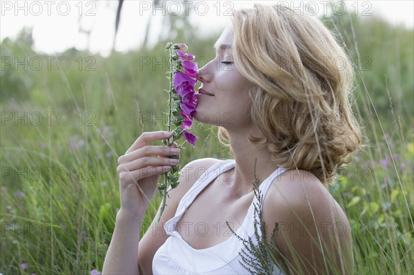 Portrait of happy woman with purple flower. Netherlands, Gelderland, Hatertse Vennen.
Photo : Jan Scherders