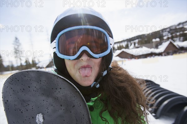 Girl with snowboard sticking out her tongue. USA, Montana, Whitefish.
Photo : Noah Clayton