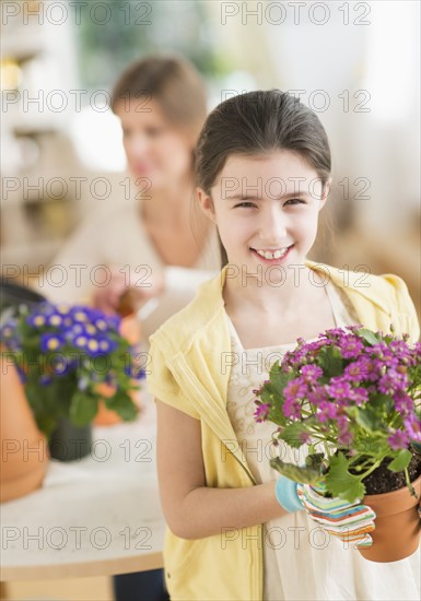 Girl (8-9) and mother potting flowers.