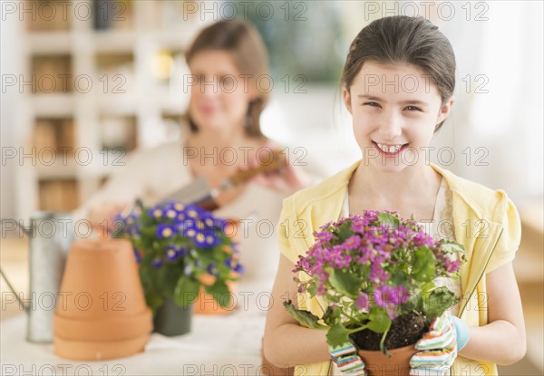 Girl (8-9) and mother potting flowers.