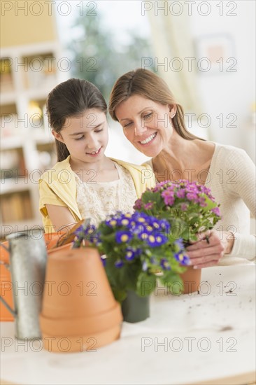 Girl (8-9) and mother potting flowers.