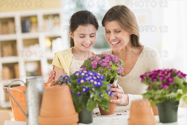Girl (8-9) and mother potting flowers.
