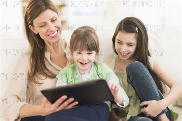 Mother and daughters (4-5, 8-9) using tablet pc.