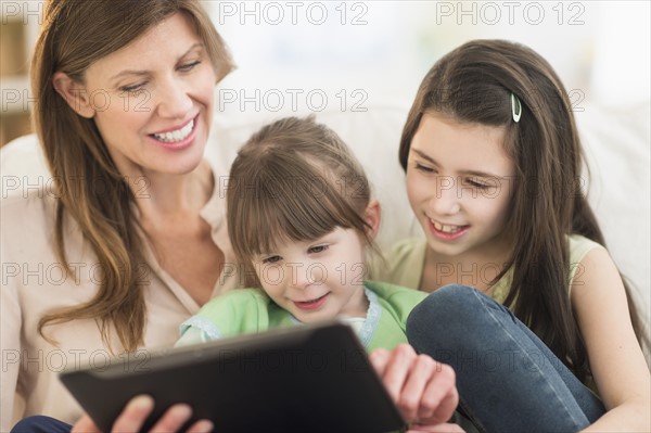 Mother and daughters (4-5, 8-9) using tablet pc.