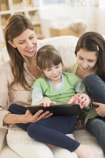 Mother and daughters (4-5, 8-9) using tablet pc.