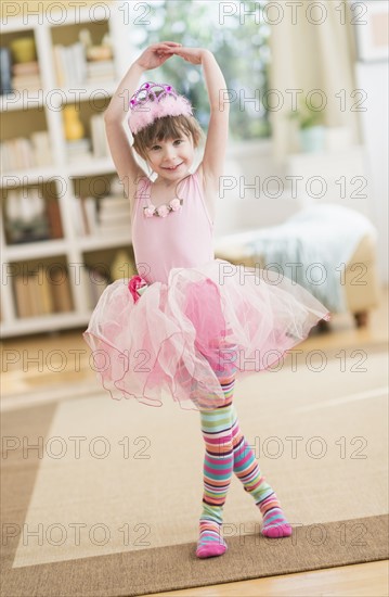 Girl (4-5) wearing tutu dancing in living room.