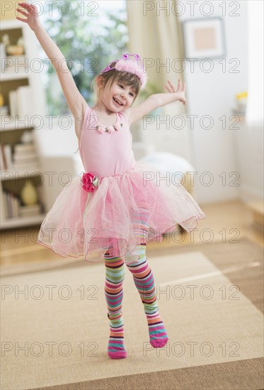 Girl (4-5) wearing tutu dancing in living room.