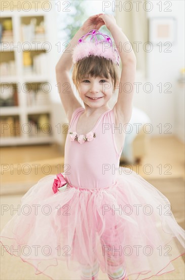 Girl (4-5) wearing tutu dancing in living room.