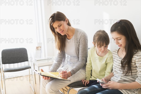 Woman and girls (4-5, 8-9) in waiting room.