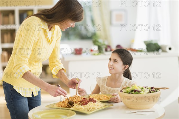 Mother and daughter (8-9) eating pasta.