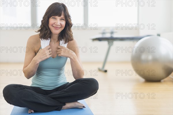 Portrait of woman sitting on mat in gym.