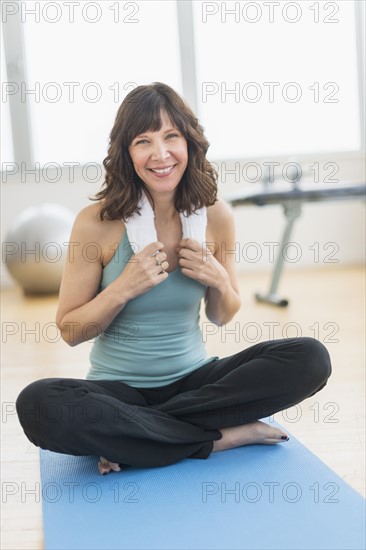 Portrait of woman sitting on mat in gym.