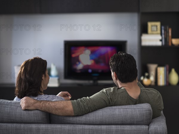 Rear view of couple watching tv.