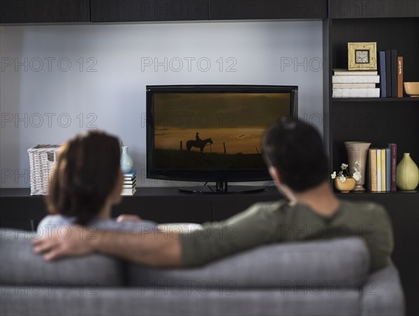 Rear view of couple watching tv.