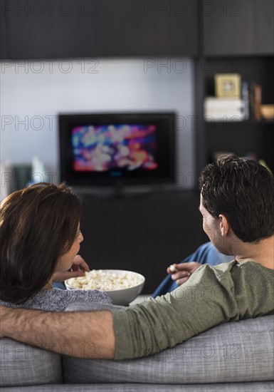 Rear view of couple watching tv.