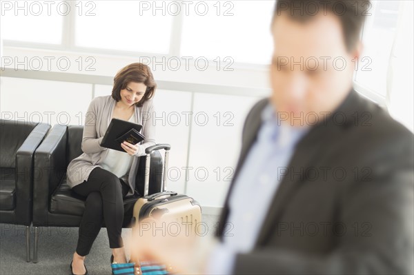 Businessman and businesswoman waiting for flight at airport.