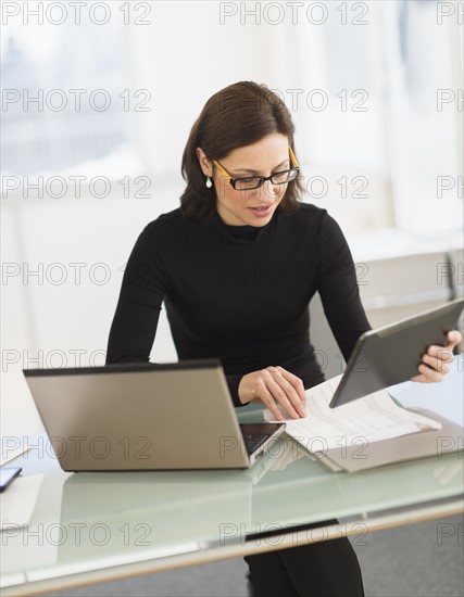 Businesswoman working on laptop and digital tablet.